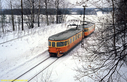 Elmotorvagnar passerar under bron vid Östertysslinge hållplats den 16 februari 1985. - klicka för att förstora