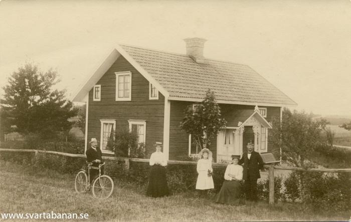 Fem personer framför huset Sandtorp i södra utkanten av Fjugesta omkring början av 1910-talet. - klicka för att stänga rutan