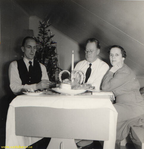 Stationskarl Helge Eklund fikar på julaftonen 1955 tillsammans med stationsmästare Hugo Lindgren och hans hustru. - klicka för att förstora